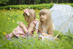 Девочки на зеленой цветущей лужайке