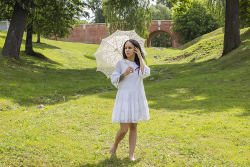 Девушка в белом платье с ажурным зонтиком на зеленой лужайке